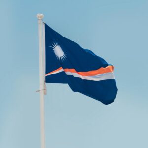 The flag of the Republic of the Marshall Islands, featuring a blue background with two stripes of white and orange, and a white star in the upper left corner.