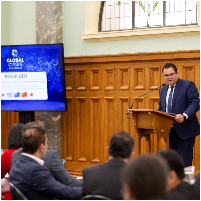 Aupito William Sio, Associate Minister of Foreign Affairs & Trade, standing at a podium and speaking into a microphone during the Global Cities New Zealand Forum.