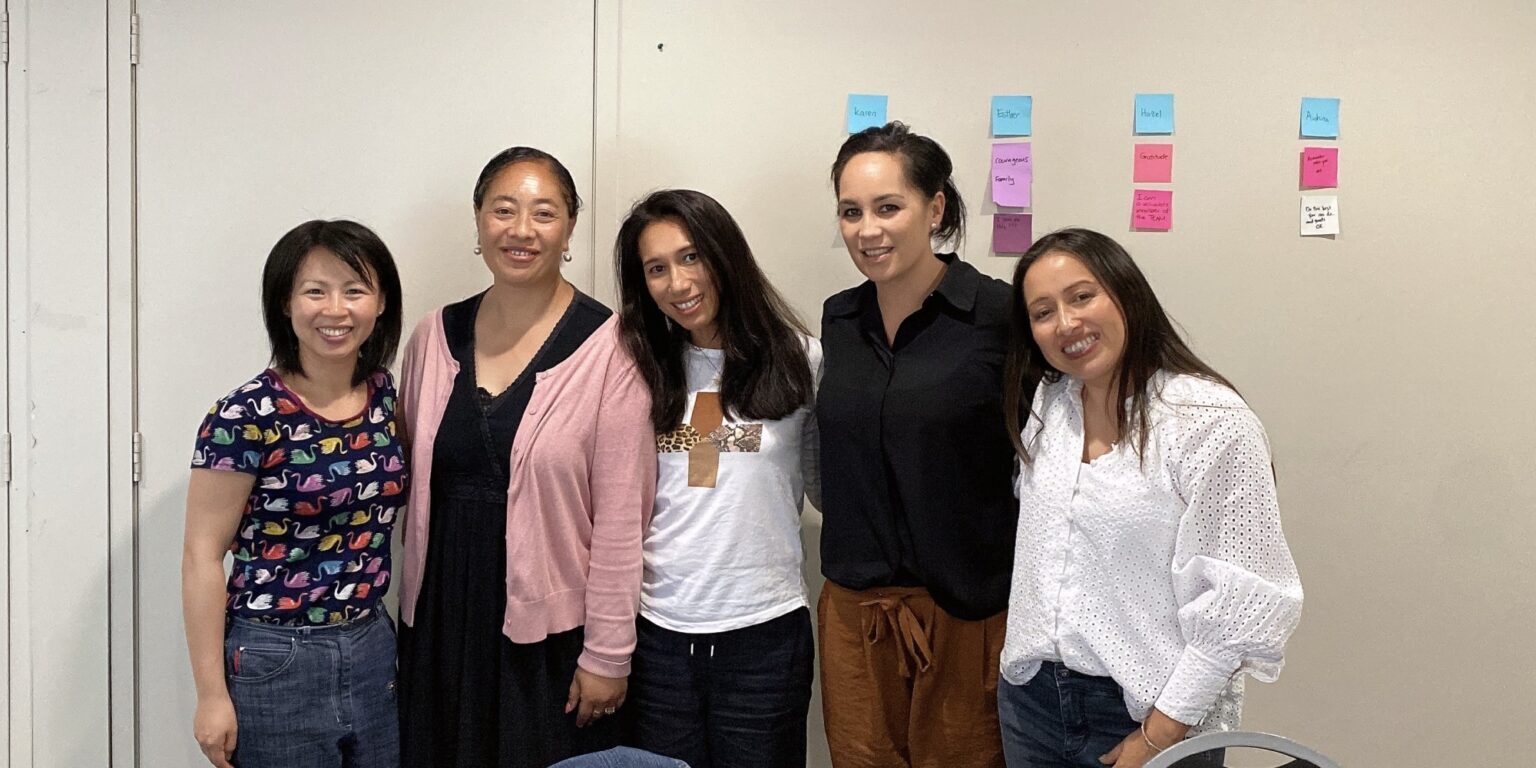 A group photo of four women of color and the founder of Accentuated, a leadership program, celebrate after one of the sessions